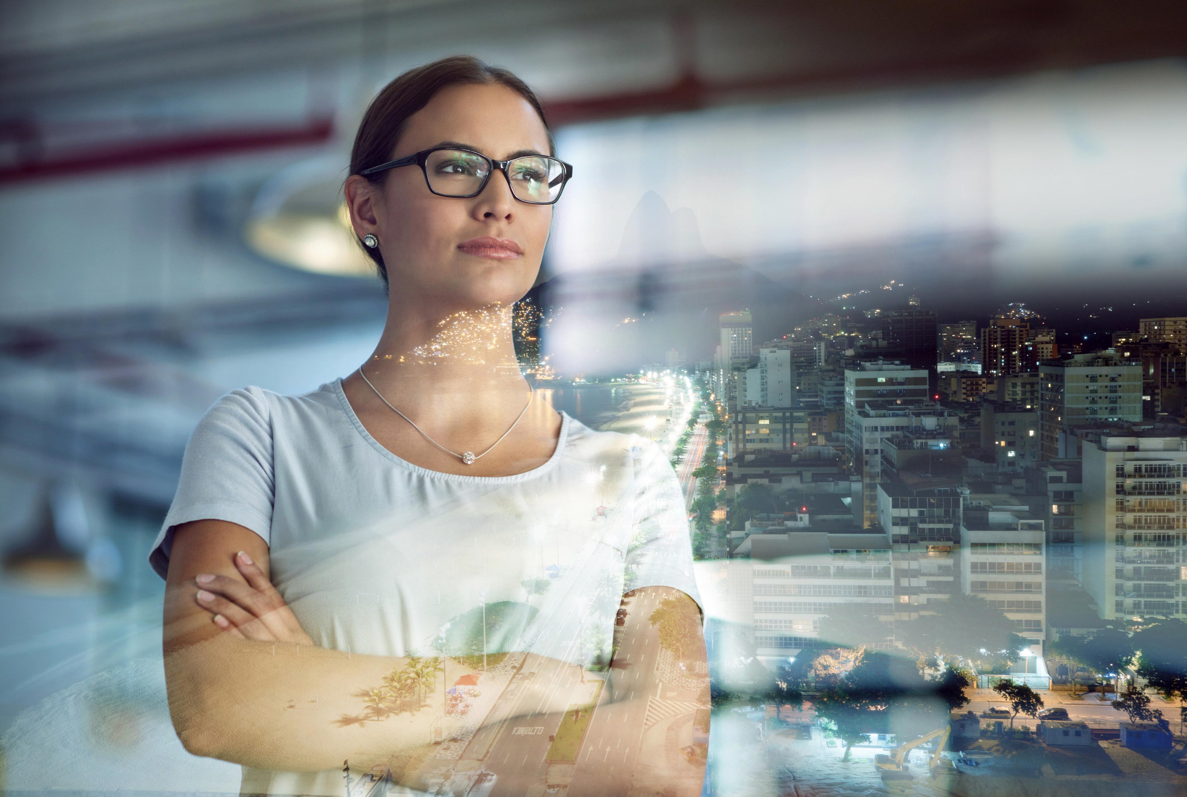 Multiple exposure shot of a young businesswoman superimposed over a city background at night